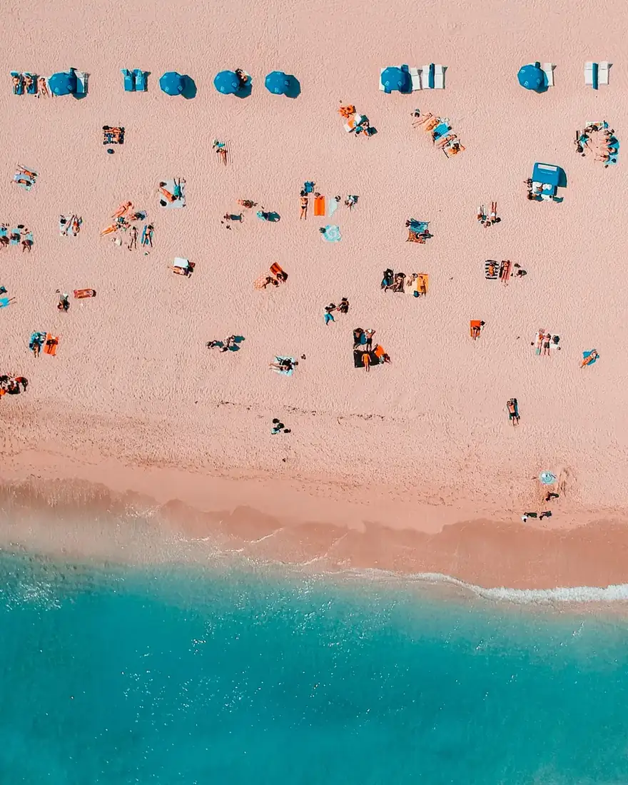 Beach spotted with people and parasols.