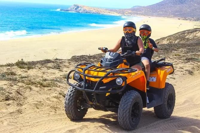 And adult and a child riding an ATV on the desert near the beach of Cabo. 