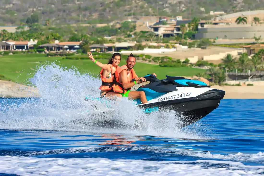 Man and woman riding a jet ski on the clear waters of Cabo. 