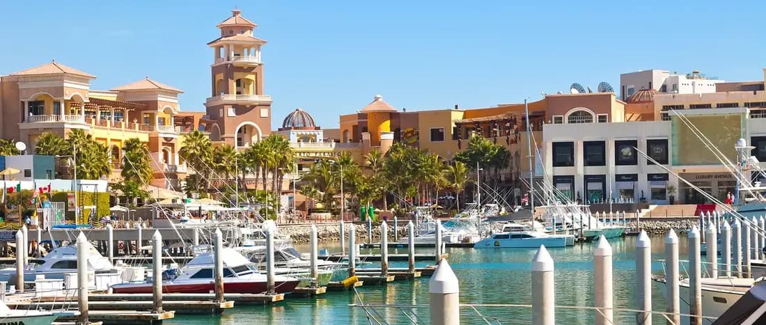 Puerto Paraiso mall seef through the marina with boats and palm trees in front of it.