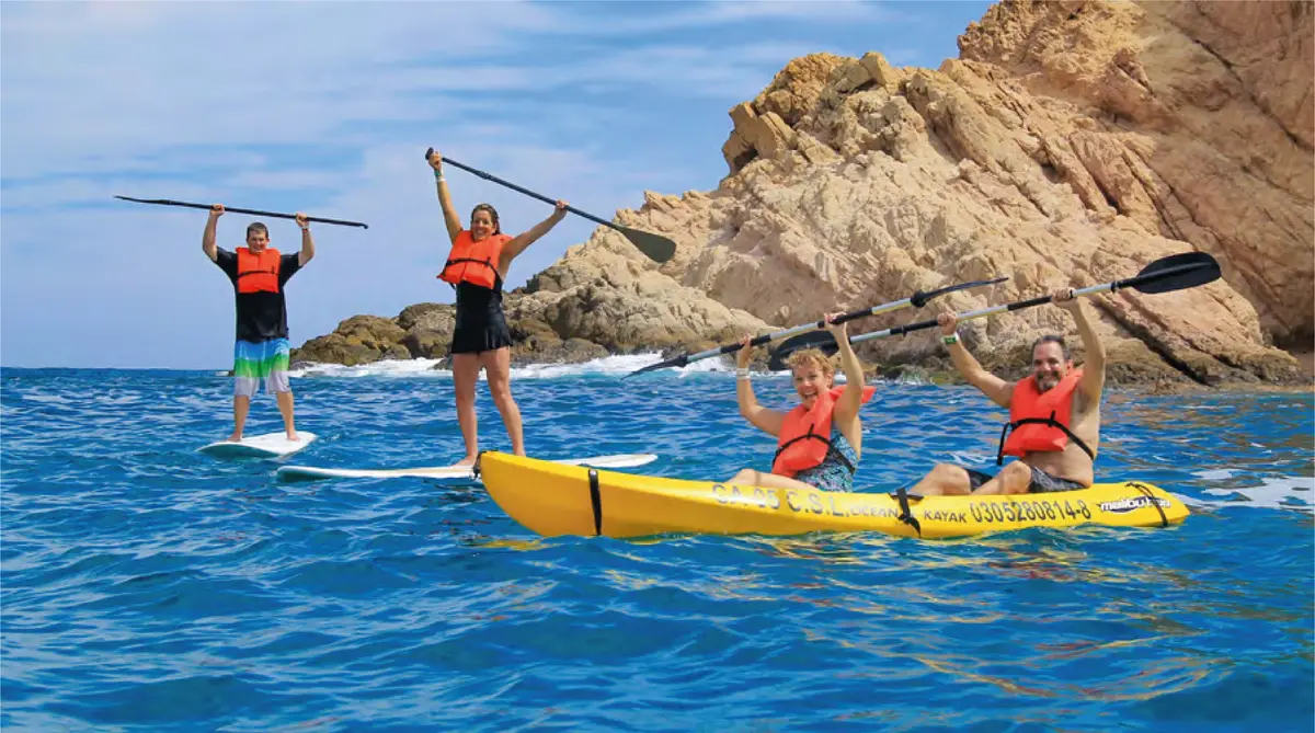 Two guys on paddle boards and two girls on a kayak in the Sea of Cortes.