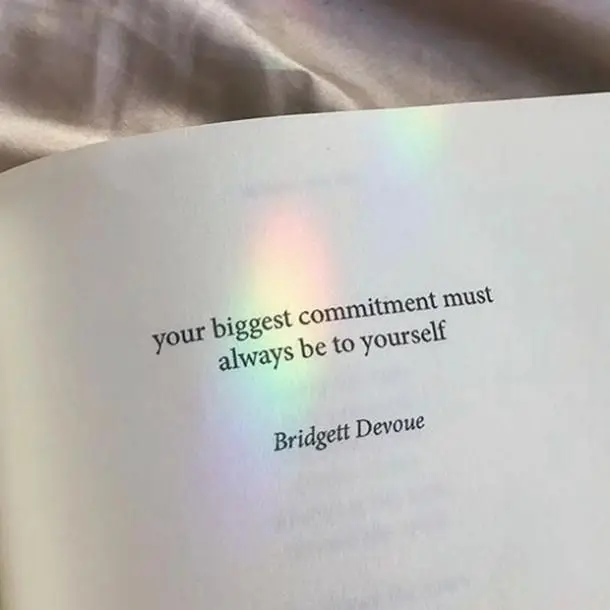 Rainbow reflected on a book that reads "your biggest commitment must always be to yourself -Bridgett Devoue"