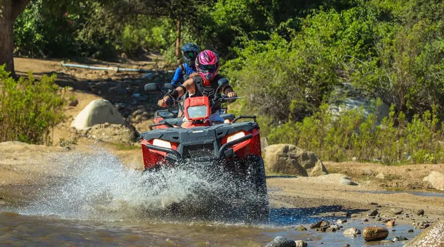 UTV riding through desert terrain, splashing through puddles. 