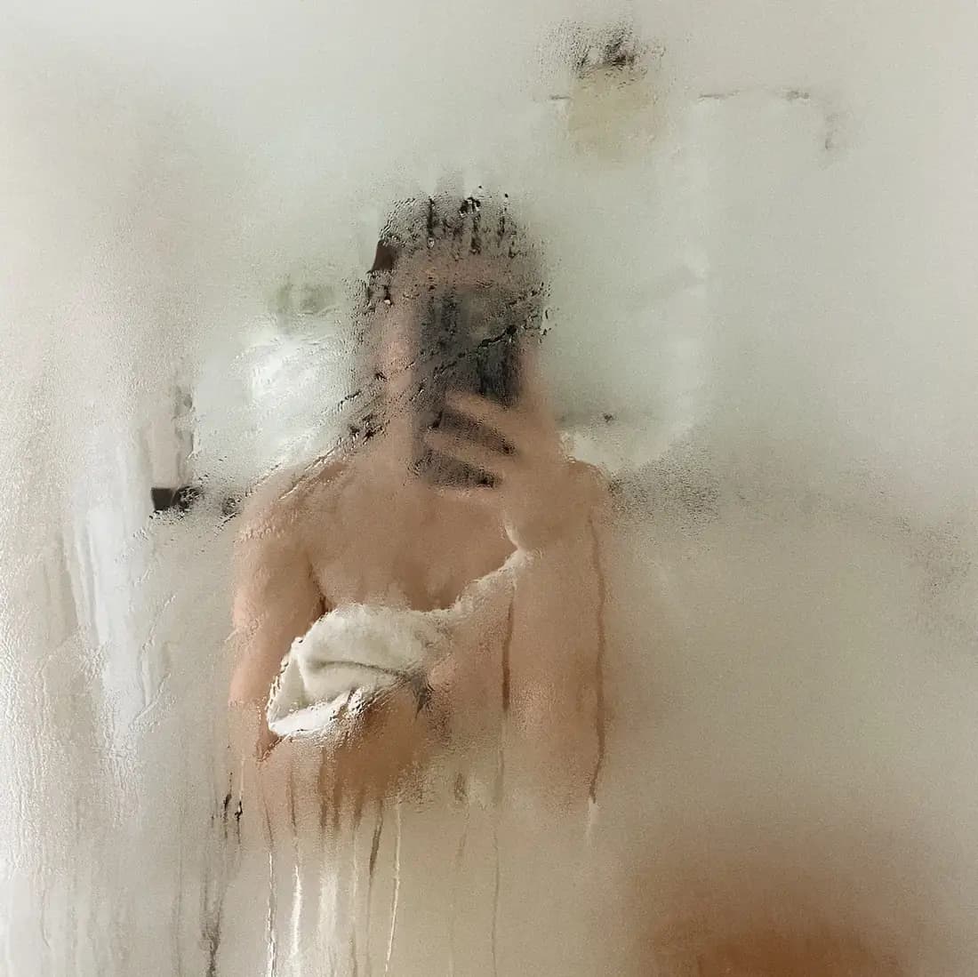 Woman taking a selfie in a steamy mirror. 