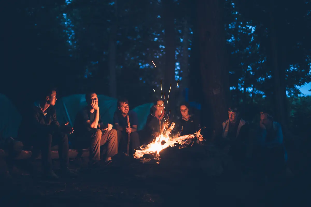 Group of friends gathered around a bonfire, sharing spooky stories. 