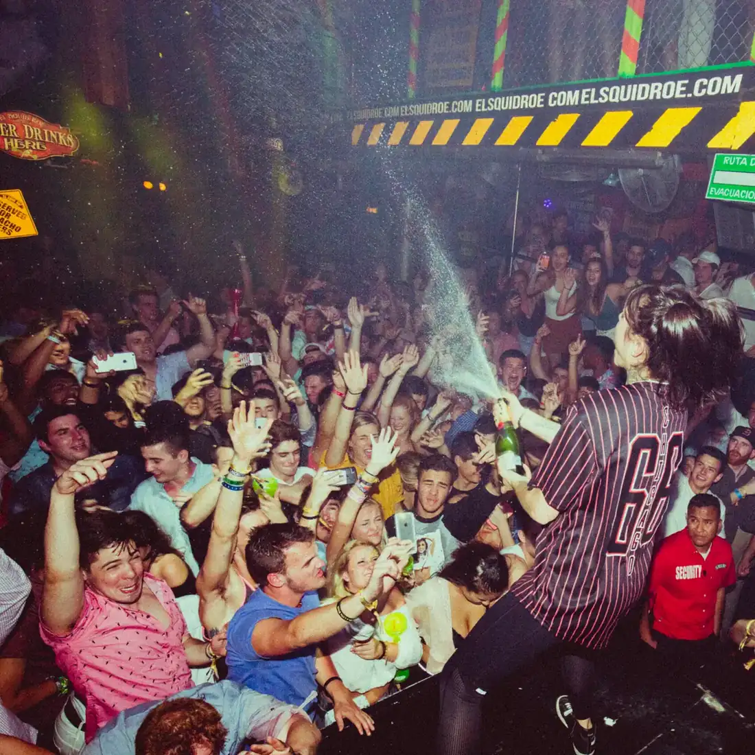 Krewella spraying a bottle of champagne on the crowd at El Squid Roe in Cabo, Mexico. 