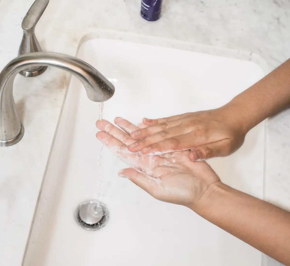 Person washing their hands in a sink. 