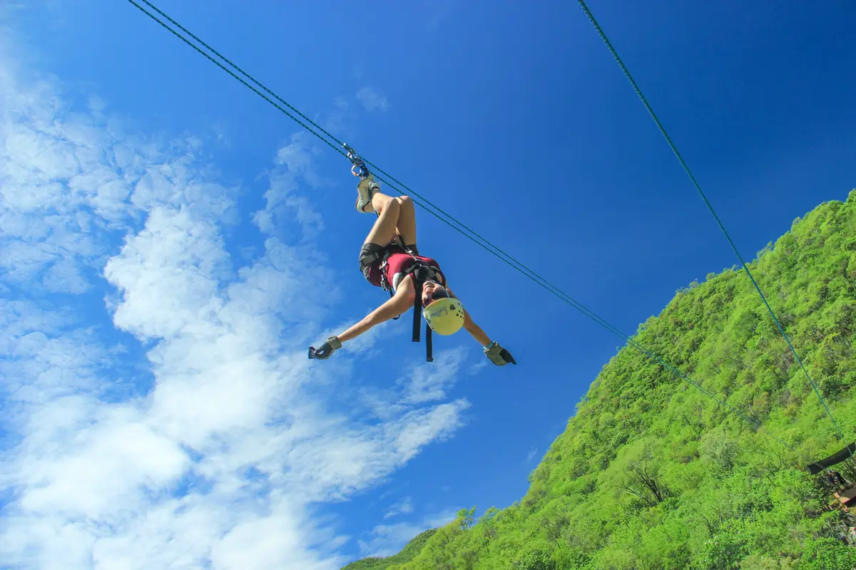 Woman hanging from the zip line, leaning back. 