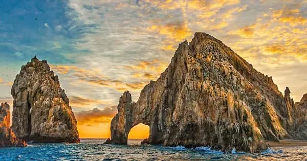 Stunning orange and blue sunset behind the Arch of Cabo, seen from the Sea of Cortez.