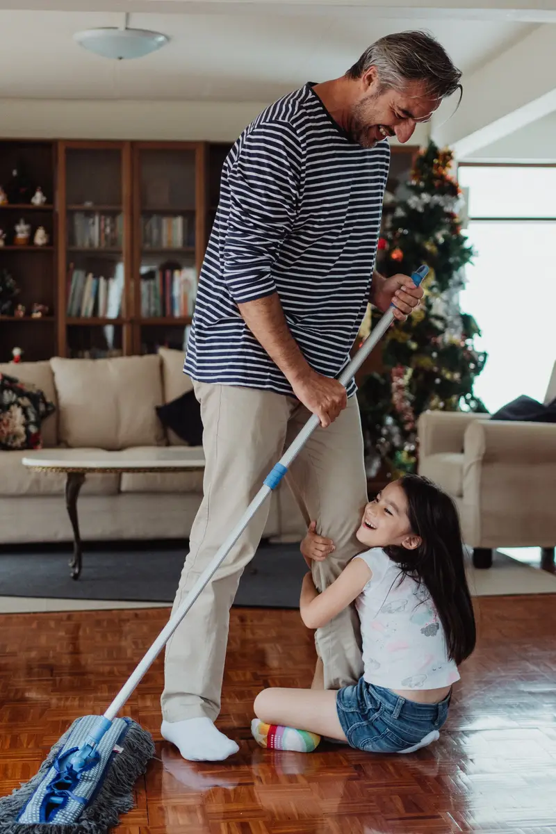 Man sweeping with the help of his daughter.