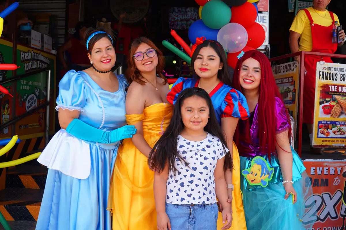 Girl posing with four princesses at the entrance of El Squid Roe in Cabo, Mexico. 