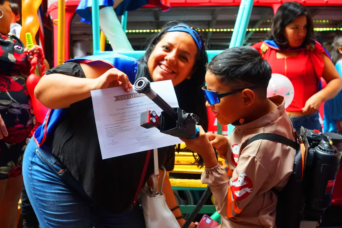 Kid dressed up as a Ghostbuster and his mom accepting his prize for best costume. 