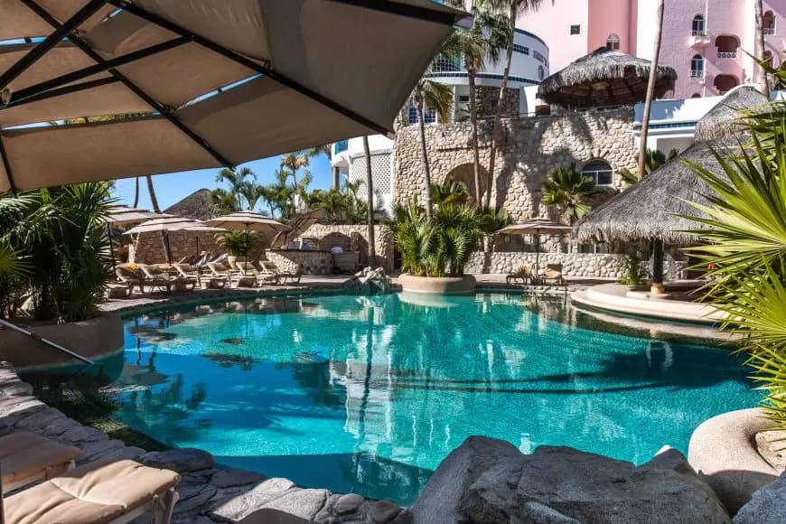 Pool seen from under a parasol, surrounded by greenery. 