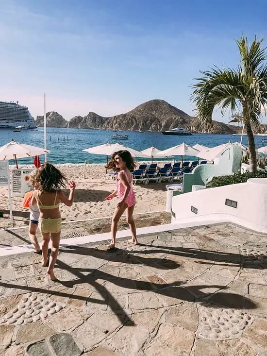 Two girls running towards the beach from their hotel. 