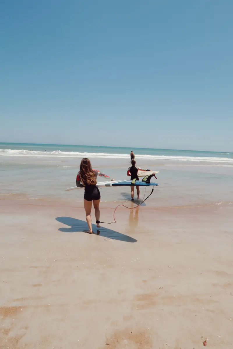 Group of people walking into the ocean with their paddle boards in Cabo, Mexico. 