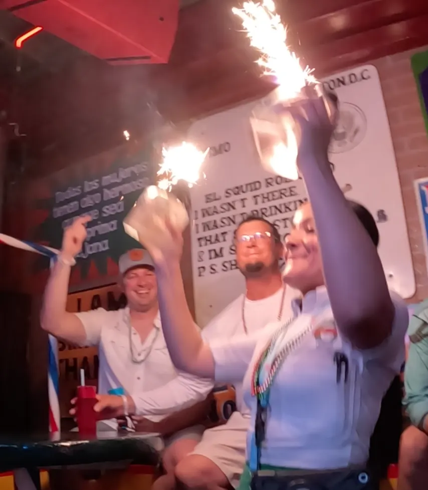 Female server giving two guys their bottles of DonJulio 70 with sparklers. 