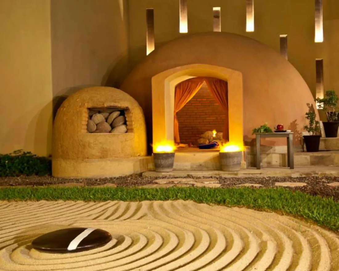 Dome sweat lodge with a large zen garden in front of it.