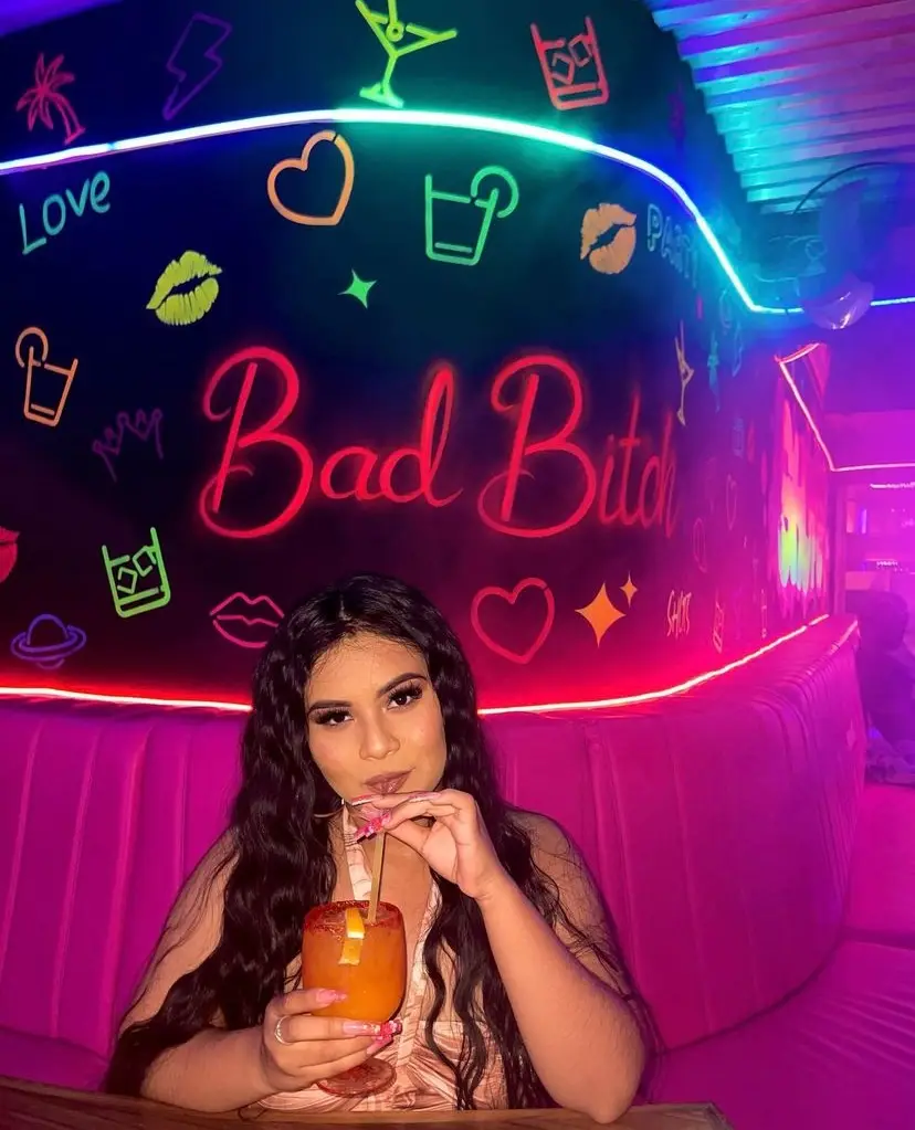 Girl sipping her drink in front of a muran at Cabo Shots in Mexico.