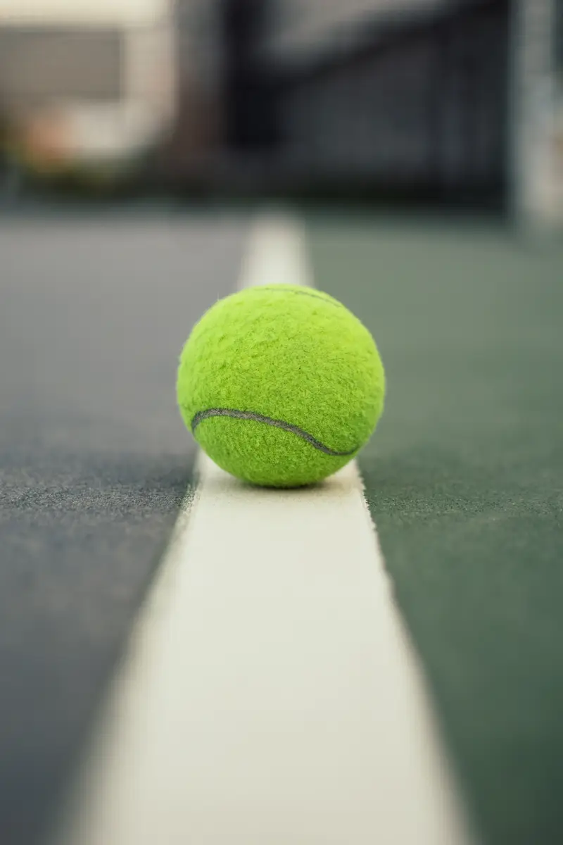 Tennis ball on a line on a tennis court.