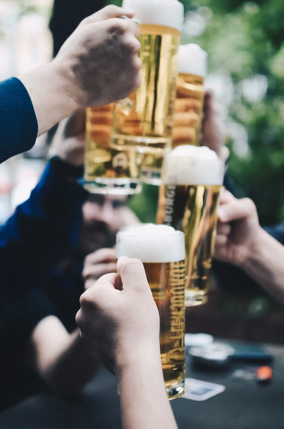 Four beers being held together for a toast.