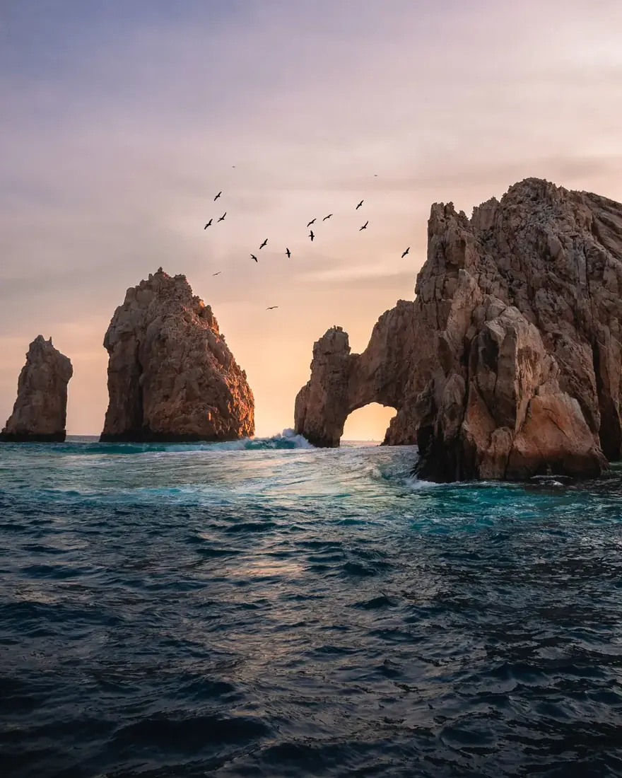 The Arco of Cabo San Lucas, Mexico at sunset with pink and purple colors in the sky.