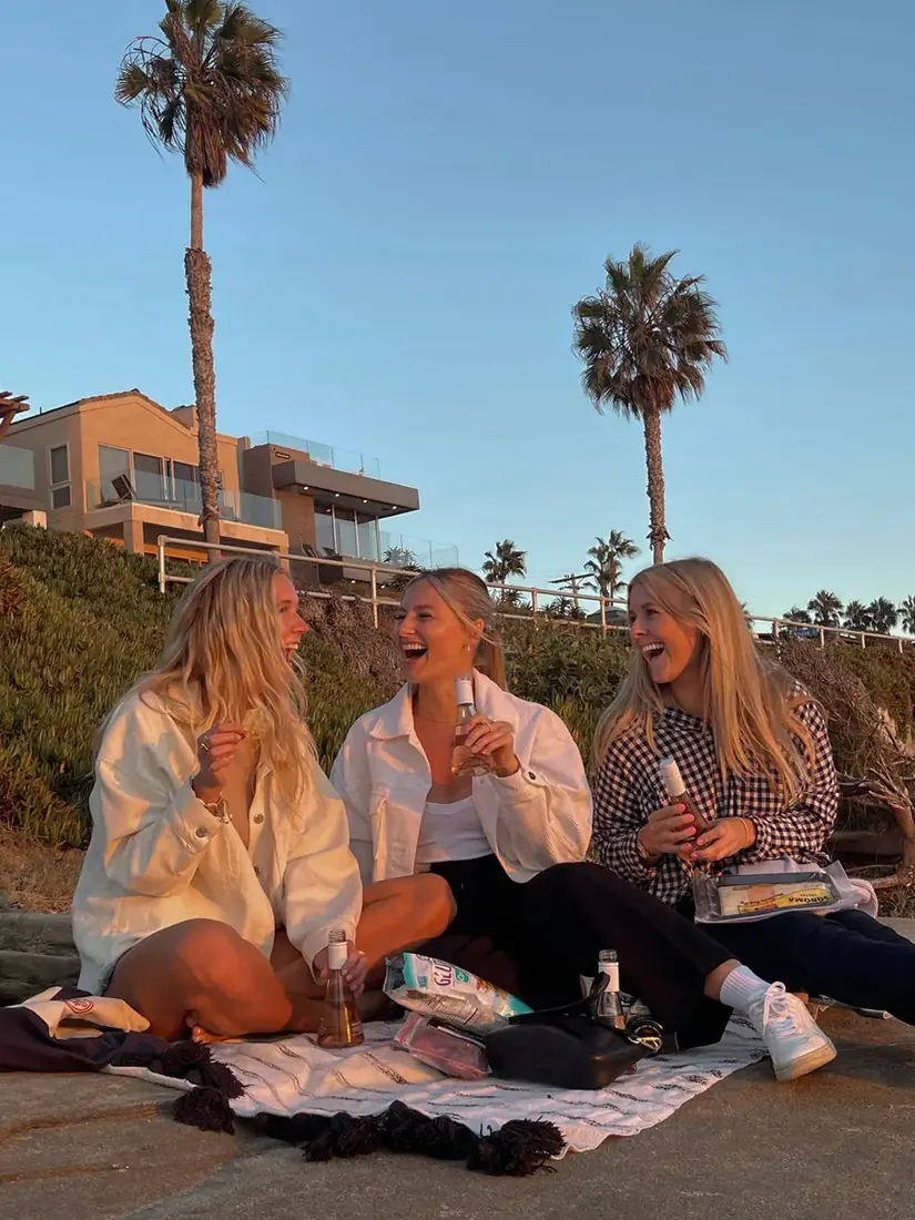 Three girls sitting at the beach sharing conversation.