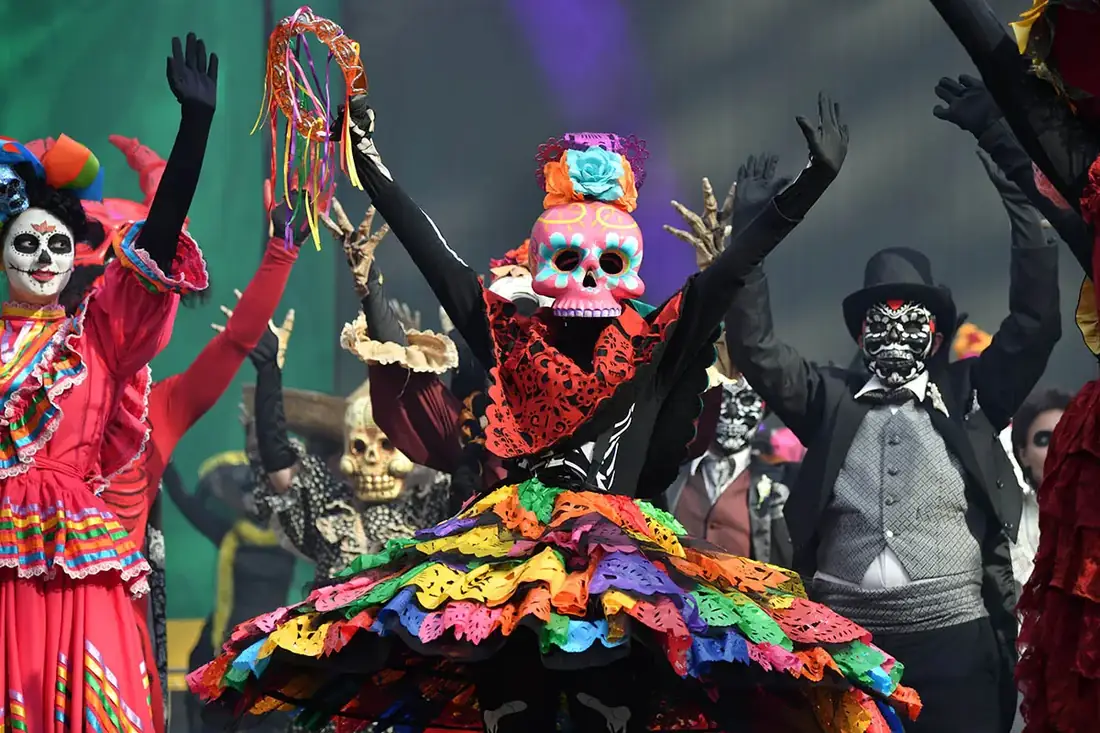 Various dancers dressed as skeletons doing a folk dance on a stage.