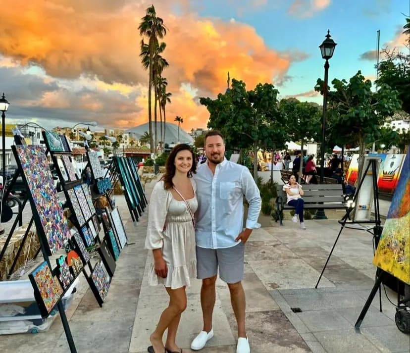 Couple posing in front of the paintings for sale at the Art Walk of Cabo in Mexico.