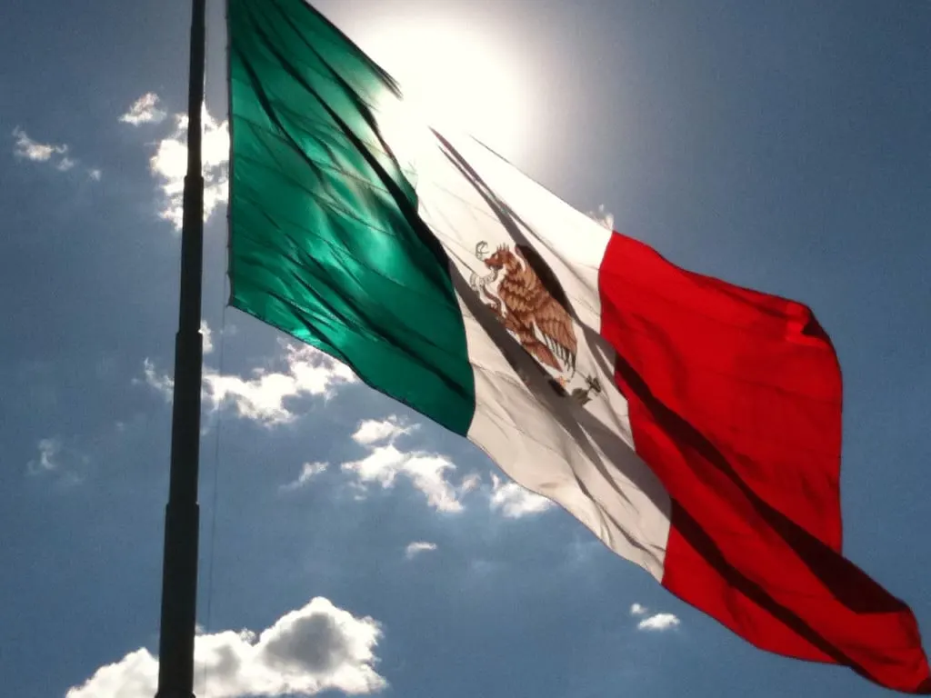 Superhero shot of Mexican flag, with the sun shining through it.
