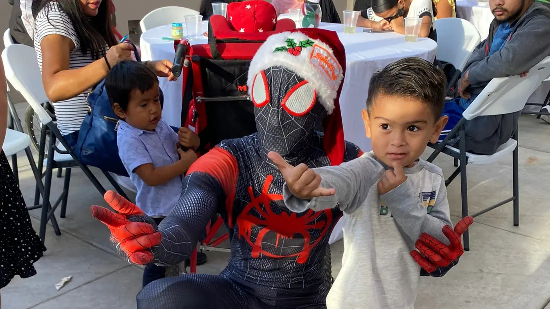 Kid posing with Spider Man wearing an El Squid Roe Christmas hat in Cabo, Mexico.