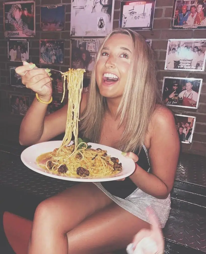 Woman enjoying a plate of fettuccine Alfredo with shrimp at El Squid Roe.