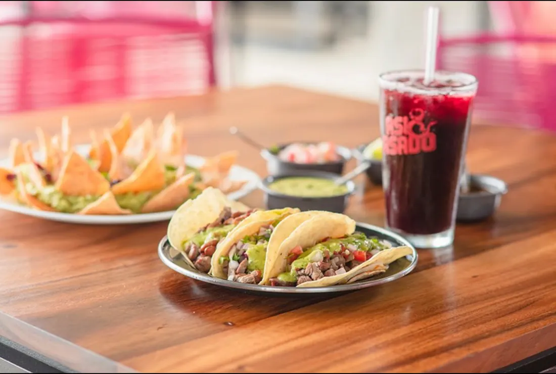 Beef tacos topped with salsas and served with a Coca Cola.