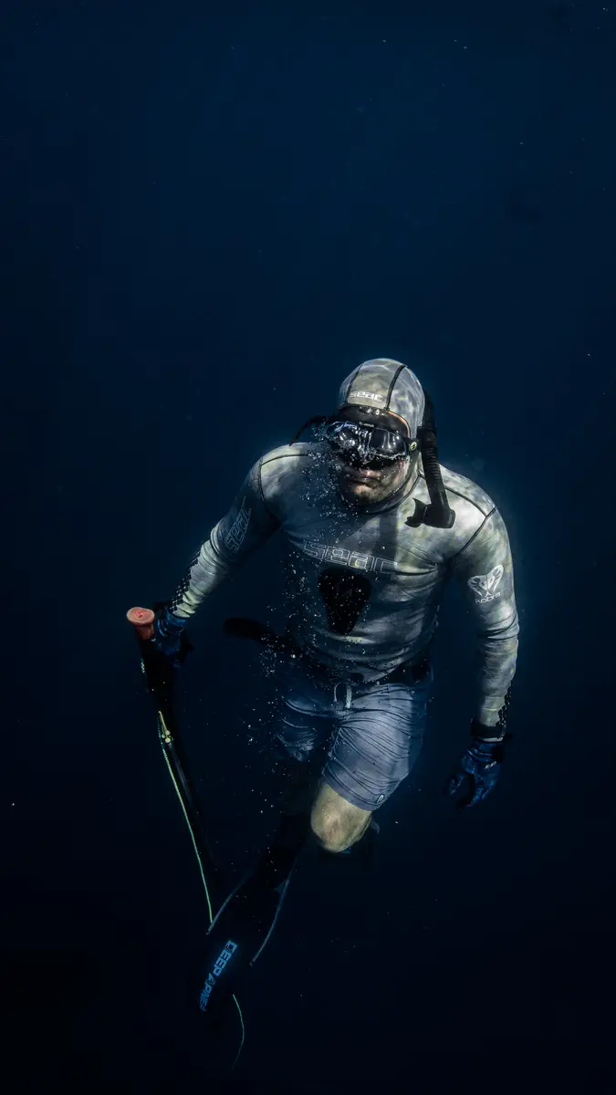 Man underwater with snorkel gear on and spear in his hand.
