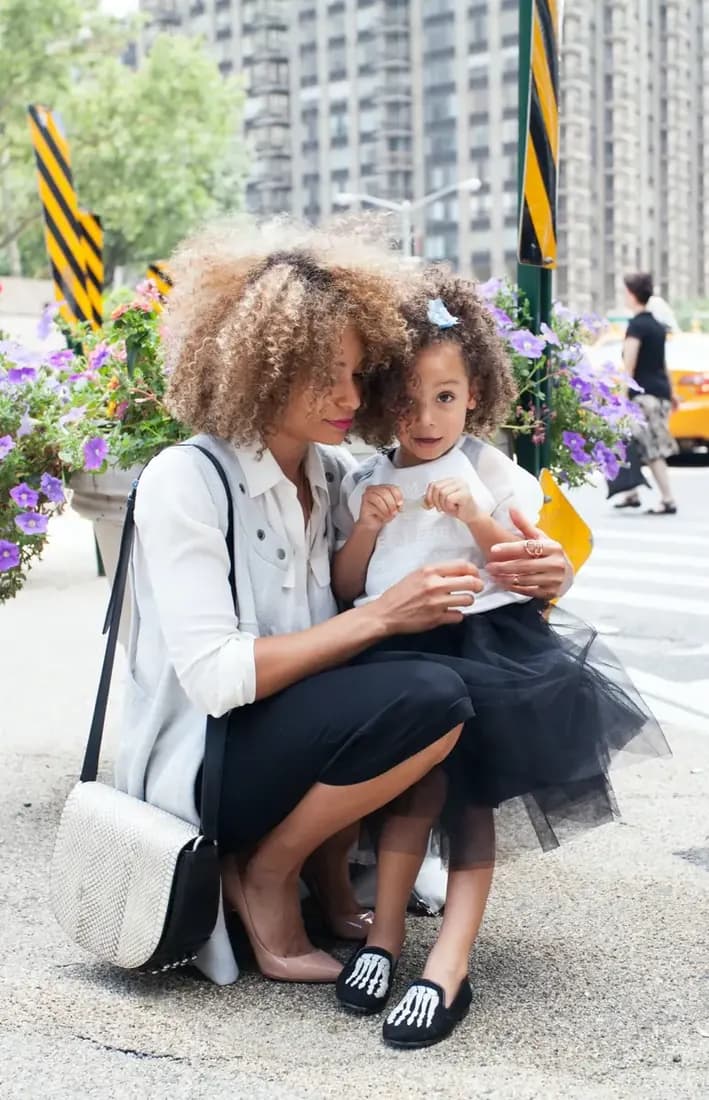 Stylish mother and daughter talking on the street.