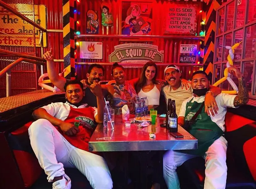 Happy guests posing with staff members at El Squid Roe in Cabo, Mexico.