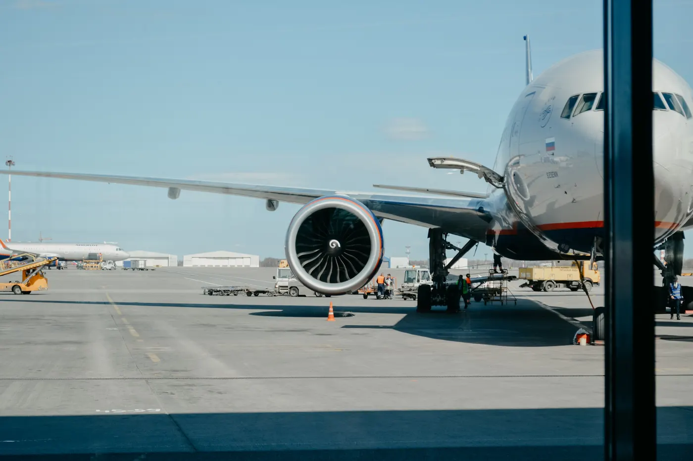 Airplane seen from the inside of an airport on a bright, clear day.