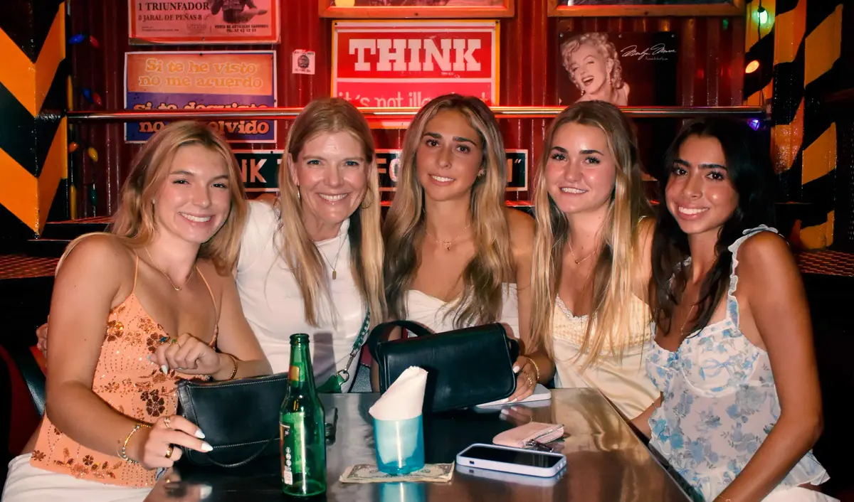 Group of women smiling and enjoying the night at a table in El Squid Roe, Cabo San Lucas