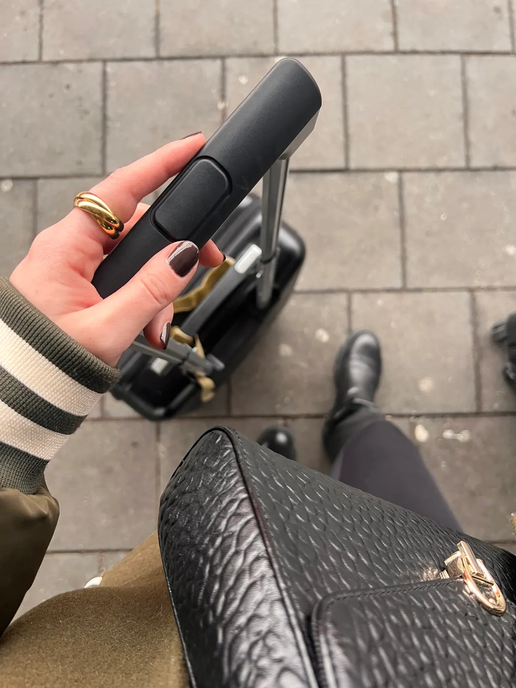 Woman holding her carry-on that matches her outfit, seen from slightly above.