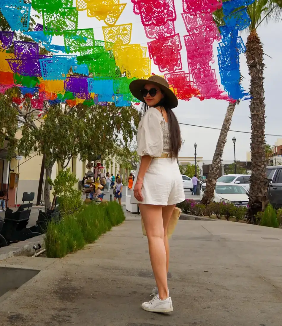 Woman posing under colorful papel picado in Cabo, Mexico.